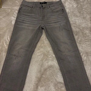 Grå jeans från Brandit W32 L34 - Snygga grå jeans från Brandit med diskreta slitningar framtill. Klassisk femficksmodell med raka ben och normal passform. Perfekta till sneakers eller boots och funkar året runt. Jeans i jätte bra skick knappt använda 9,7/10 dem har används någon enstaka gång. Storlek 32/34. Hör av vid frågor 