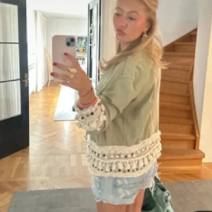 Trendig khakigrön jeansjacka från Zara - Säljer en superfin grön jacka med vita fransar. Jackan har knappar framtill och är långärmad. Perfekt för både höst och vår! 