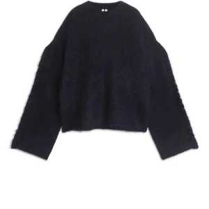 Mörkblå Arket Tröja - Säljer en mörkblå stickad tröja från Arket i mohair med oversized passform och långärmade, breda ärmar. Tröjan har en fluffig yta som ger en mysig vibe och passar perfekt när du vill ha något extra comfy. Volanger på ärmarna. Pris kan diskuteras vid snabb affär! Nypris 990kr, sällan använd så inprincip nyskick, säljs inte längre