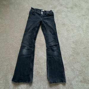 Svarta bootcut jeans Gina Tricot 152 - Snygga svarta jeans från Gina Tricot i storlek 152. Modellen har bootcut-ben och två knappar fram,. Perfekt för dig som tycker om ett par sköna och snygga jeans. Materialet är jeans med skön stretch.