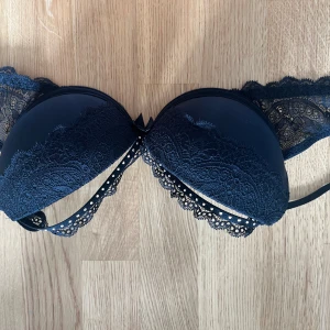 Svart spets bandeau från H&M - Snygg svart bandeau med vadderade kupor och detaljerad spets runtom. Axelbandslös modell med dekorativ snörning framtill och fina spetskanter. Perfekt för dig som vill ha en stilren och feminin look under kläderna.