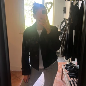 Svart skepparkavaj från 157, XS - Svart skepparkavaj från 157 i ullblandning, med stora knappar framtill och på ärmsluten. Jackan har klassisk krage. Perfekt för dig som gillar stilrena och trendiga plagg!!