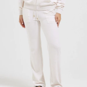  Juicy Couture - Snygga vita mjukisbyxor med raka ben och dragsko i midjan. Byxorna har två stora fickor framtill och är tillverkade i mjukt material som känns skönt mot huden. Perfekta för chill dagar eller när du vill vara bekväm men ändå se fräsch ut.