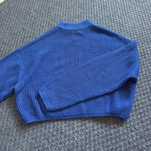 Blå stickad tröja med ribbad struktur - Säljer en blå stickad tröja med ribbad struktur och långärmade ärmar. Tröjan har en enkel, klassisk design med rund hals och är perfekt för dig som gillar en chill och stilren look. Passar dig som vill ha något mjukt och varmt till hösten eller vintern.