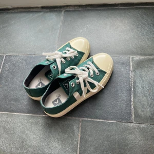 Gröna Veja sneakers med vit sula - Säljer ett par snygga Veja sneakers i mörkgrönt med vit sula och tå. Skorna har  rund tå, vita snören och metallöglor. Dom är i väldigt bra skick och har inte använt dom alls många ggr.
