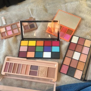 Flera ögonskuggspaletter i olika färger - Fem olika ögonskuggspaletter med både matta och skimrande nyanser. Färgerna sträcker sig från neutrala beige och bruna toner till starka färger som gul, blå, grön och röd. Paletterna har plastförpackning och vissa har spegel. Perfekt för att skapa kreativa och färgglada looks.