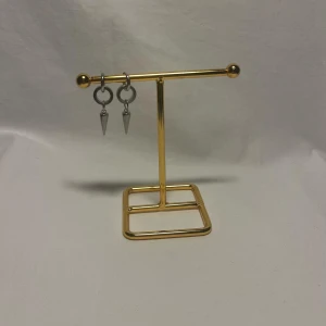 Silvriga örhängen med spetsig hängande detalj - Säljer ett par coola silvriga örhängen med rund ring och hängande spetsig konformad detalj. Perfekt för dig som gillar edgy och minimalistisk stil. Passar till både streetwear och mer stilrena outfits.