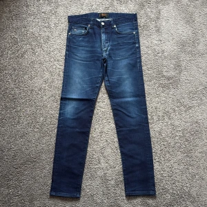 Mörkblå jeans från J.Lindeberg - Snygga mörkblå skinny jeans från J.Lindeberg med klassisk femficksdesign och diskret logga på myntfickan. Jeansen har en smal passform, raka ben och är tillverkade i stretchigt denim för extra komfort. Perfekta för dig som gillar stilrena och moderna jeans.