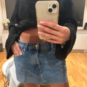 Blå jeanskjol mini - Säljer en klassisk blå jeanskjol i minilängd med normal längd, och stängs med knapp och dragkedja framtill. Perfekt att styla med en croppad tröja eller t-shirt.