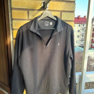Svart tröja med halv dragkedja från Polo Ralph Lauren - Säljer en riktigt snygg och trendig svart  tröja från Ralph Lauren med half zip. Tröjan är använd cirka 1 och en halv månad men är väldigt bra skick! 8/10 skick! Tröjans nypris är cirka 1600kr och jag säljer den här för endast 499kr! Kontakta vid minsta intresse!