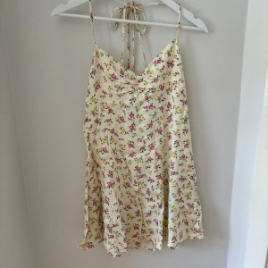 Blommig sommarklänning - Söt ljusgul kortklänning med små rosa och gula blommor. M men passar S
