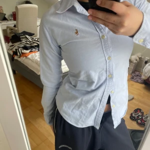 Ralph Lauren sjorta  - Klassisk ljusblå skjorta från Ralph Lauren med broderad logga på bröstet. Skjortan har lång ärm, knappar framtill och en tidlös krage. Perfekt för en stilren och enkel look. Och har aldrig använt den