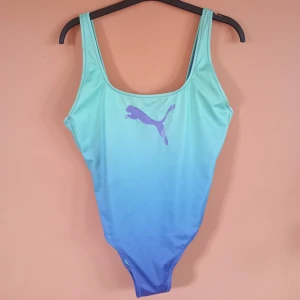 Blågrön baddräkt med Puma - Cool baddräkt med Puma i blå och grön ombre. Helt oanvänd och djup rygg med breda axelband. Finns en liten fläck på insidan - se sista bilden 🌊 Finns tyvärr ingen lapp för storlek men skulle uppskatta till Storlek M 