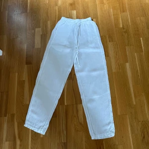 Vita linnebyxor med dragsko - Säljer ett par fräscha vita linnebyxor från Chelsea med elastisk midja och dragsko. Byxorna har raka ben och är perfekta för varma dagar. Lätta och luftiga, passar till många olika outfits.