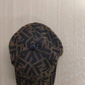 Fendi keps  - Säljer en brun och svart keps från Fendi med det klassiska FF-mönstret över hela kepsen. Justerbar rem baktill i läder. Perfekt accessoar för dig som gillar lyxiga detaljer och streetstyle.