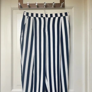 Svartvita randiga kostymbyxor - Snygga kostymbyxor med breda svarta och vita vertikala ränder. Byxorna har normal passform, hällor för bälte och fickor både fram och bak. Perfekta för dig som vill sticka ut med en trendig look.