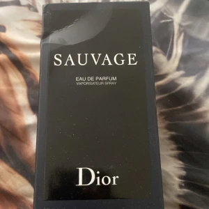Sauvage Eau de Parfum från Dior - Sauvage Eau de Parfum från Dior med elegant svart glasflaska och tydlig logotyp. Parfymen har en maskulin och fräsch doft, perfekt för dig som gillar exklusiva och moderna dofter. Flaskan har rund form och svart lock med CD-logga.
