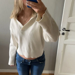 Vit croppad stickad tröja med v-ringning - Säljer en vit croppad stickad tröja med v-ringning och långa ärmar från BikBok