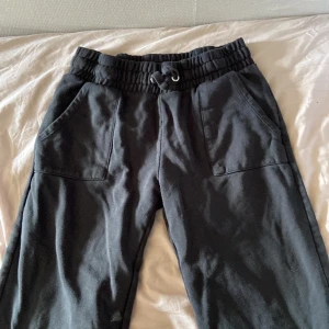 Svarta mjukisbyxor med snörning - Svarta mjukisbyxor med resår och snörning i midjan. Byxorna har två sidofickor fram och två bakfickor. Perfekta för en avslappnad stil och sköna att ha på sig hela dagen. ca 70 cm i benen. OBS! sömmen vid anklarna har gått upp.