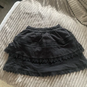 Svart kjol med spetsdetaljer - Säljer en söt svart kjol med spetsdetalj från Ginatricot. Storlek xs.🫶🏼