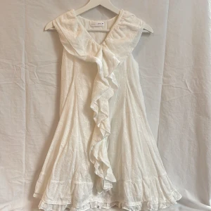 Vit volangklänning med v-ringning - Superfin vit klänning med v-ringning och stora volangdetaljer framtill. Ärmlös modell i lätt, mönstrat tyg från Zara i stlk 164