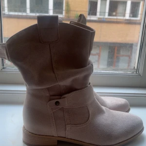 Beige mockaboots från Merley Stockholm - Säljer ett par snygga beige boots i mocka från Merely Stockholm. Skorna har låg klack, rund tå och dekorativ söm samt dragkedja på sidan. Jättesnygga inför sommaren och midsommar. Köpte för 900kr priset kan diskuteras❤️använda 1 gång