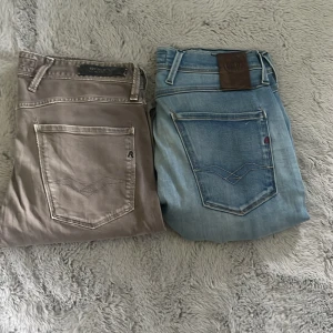 Två par jeansbyxor i olika färger - Säljer två par jeansbyxor, ett par i ljusblå denim med klassisk bakficka och ett par i grått med diskret logga på fickan. Båda har raka ben och normal passform, perfekta till vardags. Snygga detaljer och klassisk jeanslook.