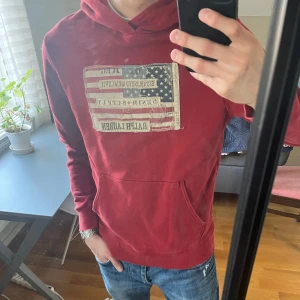 Röd hoodie Ralph Lauren - Säljer en röd hoodie från Ralph Lauren denim and supply med riktigt skönt tryck på magen. Tröjan har magficka och huva, samt långa ärmar. Perfekt för en avslappnad stil! Skicket är bra men har några lösa trådar på magen. 
