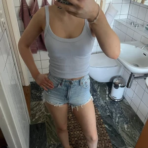Ljusblå jeansshorts från Zara - Säljer ett par ljusblåa jeansshorts från Zara med slitna toppar. 
