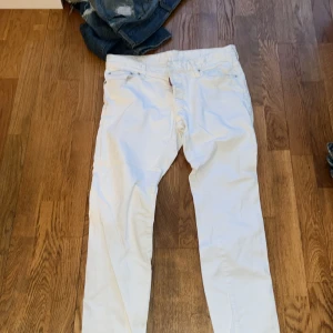 Vita jeansbyxor från Dsquared2, Nypris 5000kr - Säljer ett par vita jeansbyxor från Dsquared2 med klassisk femficksdesign och diskret Dsquared2-logga på bakfickan samt röd etikett vid fickan fram. Byxorna har normal passform och är tillverkade i bomull. Perfekta för dig som vill sticka ut med stilrena jeans!