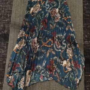 Mönstrad kjol från H&M Divided - Säljer en blå mönstrad kjol från H&M Divided i storlek 36. Kjolen har ett färgstarkt blommigt och djurinspirerat mönster med ormar och fjärilar, samt plisserad design. Perfekt för dig som gillar unika prints och vill sticka ut. Pris:300kr