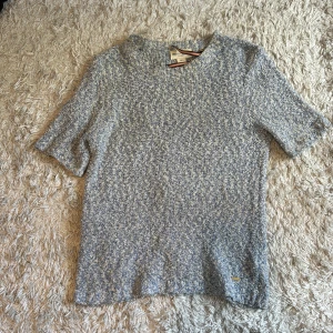 Blåmelerad stickad topp från Holly & White - Säljer en blåmelerad stickad topp från Holly & White. Tröjan har korta ärmar och rund halsringning. Materialet är mjukt och ger en avslappnad men ändå stilren look. Perfekt för vår och sommar!