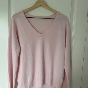 Ljusrosa v-ringad stickad tröja - Säljer en ljusrosa stickad tröja från Marks Spencer med v-ringning. Tröjan har lång ärm och är i ett tunt, mjukt material som passar perfekt till lager-på-lager. Enkel och stilren design.