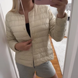 Beige lättviktsjacka - Dunjacka från Uniqlo. Den har lite defekter som svarta märken (se bild) även en sminkfläck (som säkert går att ta bort) Därav priset. Jättefin annars och det är inget man tänker på. Den är i storlek L men sitter bra på mig som har S i vanliga fall 🤍 Skriv vid frågor