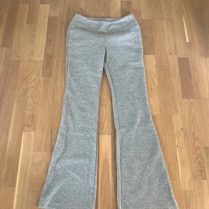 Grå mjukisbyxor med bootcut - Gråa mjukisbyxor med bootcut och hög midja. Byxorna är i mjukt material och har en bekväm passform, perfekta för en avslappnad stil. Helt oanvända.