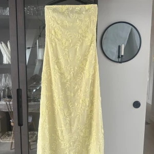 Ljusgul bandeauklänning med broderidetalj - Bandeau-klänning från Moa Mattssons kollektion tillsammans med NA-KD (helt slutsåld på hemsidan)!!💛 Säljer då jag har en annan balklänning, därför endast testat. Köpt för ursprungspris!🫶