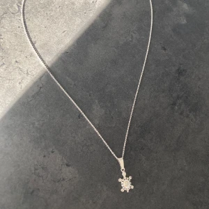 Halsband med sköldpaddshänge i silver - Säljer ett fint halsband i silver med ett unikt sköldpaddshänge. Hänget har en snäckformad detalj i mitten och kedjan är tunn och elegant. Perfekt för dig som gillar djurmotiv och stilrena smycken.