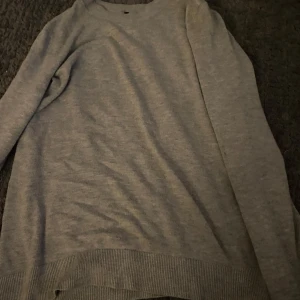 Ljusgrå stickad tröja från 157 - Säljer en enkel och stilren ljusgrå stickad tröja från 15:97. Tröjan har rund halsringning, långa ärmar och ribbade muddar vid ärmslut och nederkant. Perfekt basplagg till garderoben.