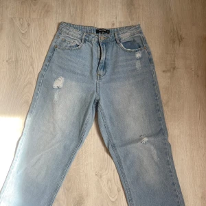 Ljusblå jeans med slitningar - Säljer ett par ljusblå jeans med snygga slitningar från missguided som knappt är använda. Storlek 34 men passar 36 också.
