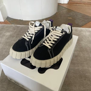 Svarta Eytys sneakers  - Svarta sneakers från Eytys med krämvit sula och vita kontrastsömmar. Modellen Odessa. Skorna har vita snören och en lila hälflik. Storlek 41 men passa också 40. Dom är helt nya, aldrig använda.💗