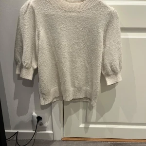 Vit stickad tröja från Vero Moda - Mysig vit stickad tröja från Vero Moda med trekvartsärmar och ribbade muddar. Perfekt för lager-på-lager och enkel att matcha med olika outfits.