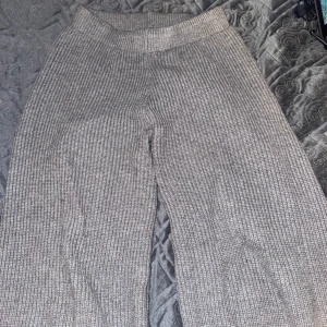 Hemma byxor - Mysiga grå stickade byxor med ribbad struktur och bred resår i midjan. Byxorna har en rak och lite lösare passform, perfekta för en avslappnad stil. Använd några gånger. Annars bra skick!!