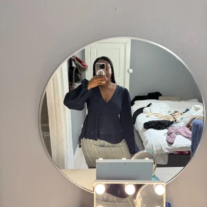 Mörkblå blus med v-ringning och volang - Säljer en mörkblå blus med v-ringning och långa ärmar. Blusen har en lätt volang nertill och är tillverkad i ett strukturerat tyg. Perfekt för dig som vill ha en stilren men ändå trendig topp.