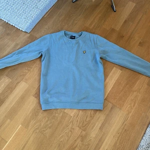 Lyle & Scott tröja - Säljer en stilren bekväm ljusblå tröja från Lyle & Scott. Använd ett fåtal gånger endast. Storleken är 14 years vilket motsvarar ungefär 164-170.