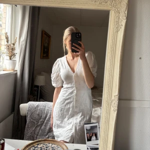 Vit klänning från H&M - Säljer en söt vit klänning från H&M med korta puffärmar och knappar framtill. Klänningen har ett diskret hålmönster och en v-ringad design som ger en romantisk känsla. Perfekt inför student, midsommar, konfirmation och andra somriga tillfällen! Klänningen är i stl S men har sytt in midjan lite då den va lite pösig och upplevdes som större än S🥰 