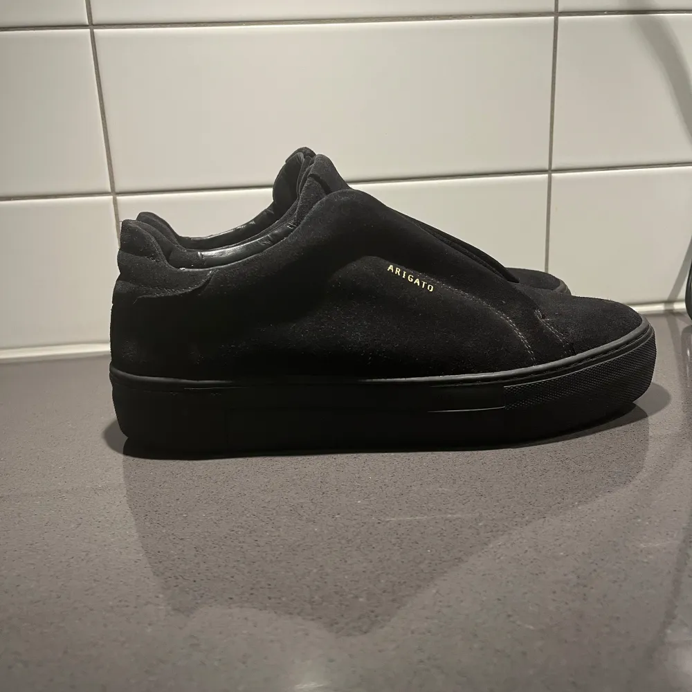 Snygga svarta sneakers från Axel Arigato i mocka. De har en stilren design med diskret logga på sidan och en bekväm passform. Perfekta för en minimalistisk look. KAN MÖTAS UPP DÄR JAG BOR. PRIS KAN DISKUTERAS . Kengät.