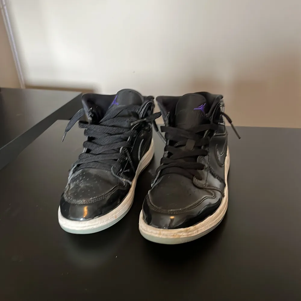 Snygga svarta Nike Air Jordans med klassisk design och snörning. Skorna har en glansig finish och vit sula. Perfekta för en stilren look.. Kengät.
