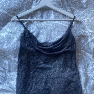 Svart glittrig topp från Even&Odd - Svart topp från Even&Odd med glittrigt material och smala axelband. Lite siden liknande material och utseende. Perfekt på exempelvis nyårsafton. Inga defekter och använd en gång