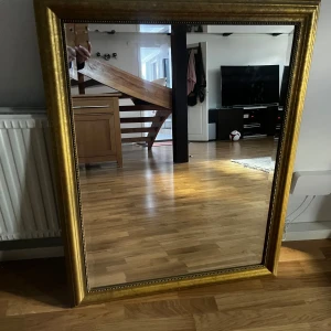 Stor rektangulär spegel med guldram - Elegant spegel med en bred guldfärgad ram och dekorativa detaljer. Perfekt för att ge rummet en lyxig känsla. Kan placeras både stående och liggande.