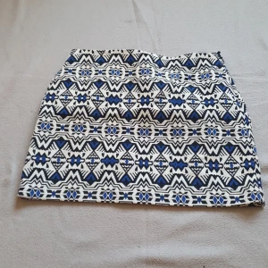 Mönstrad kjol från H&M Divided - Jaquardmönstrad mönstrad kjol från H&M Divided i svart, blått och vitt. Kjolen har ett geometriskt mönster och är perfekt för att ge din outfit en unik touch. Den är kort och har en normal passform. Använd en semester vid Medelhavet. 